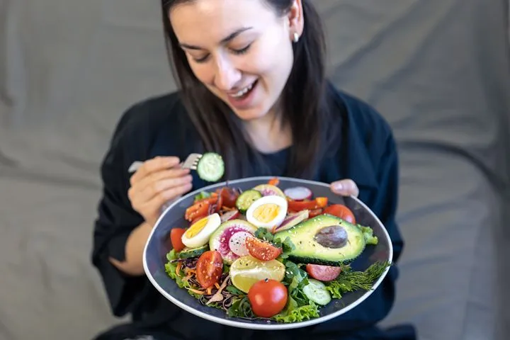 Woman eating a healthy meal mindfully at home — structured meal timing for IBS